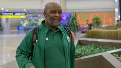 Coach Pitso Mosimane walking at an airport