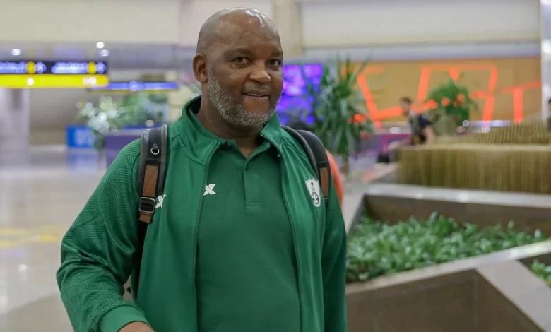 Coach Pitso Mosimane walking at an airport