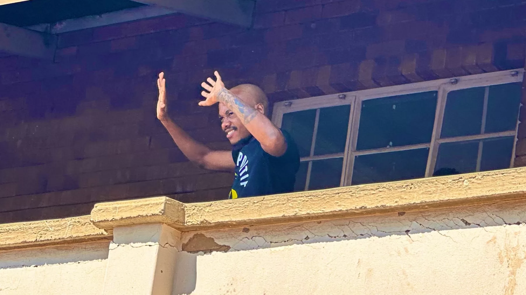 Percy Tau waving at learners in his new haircut