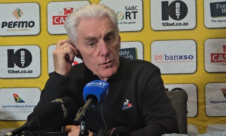 Hugo Broos holding his ear during a media briefing