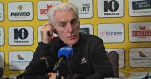 Hugo Broos holding his ear during a media briefing